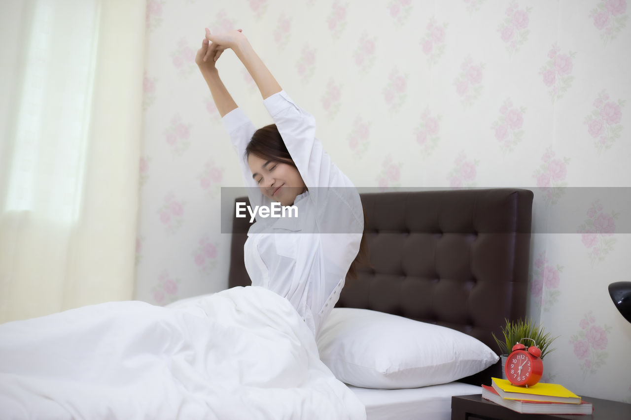 MIDSECTION OF WOMAN RELAXING ON BED