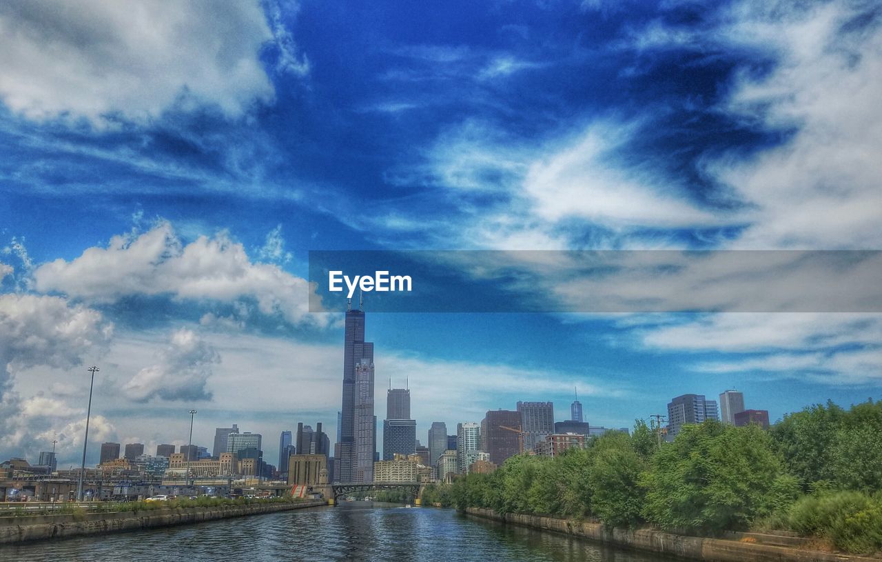 City at waterfront against cloudy sky