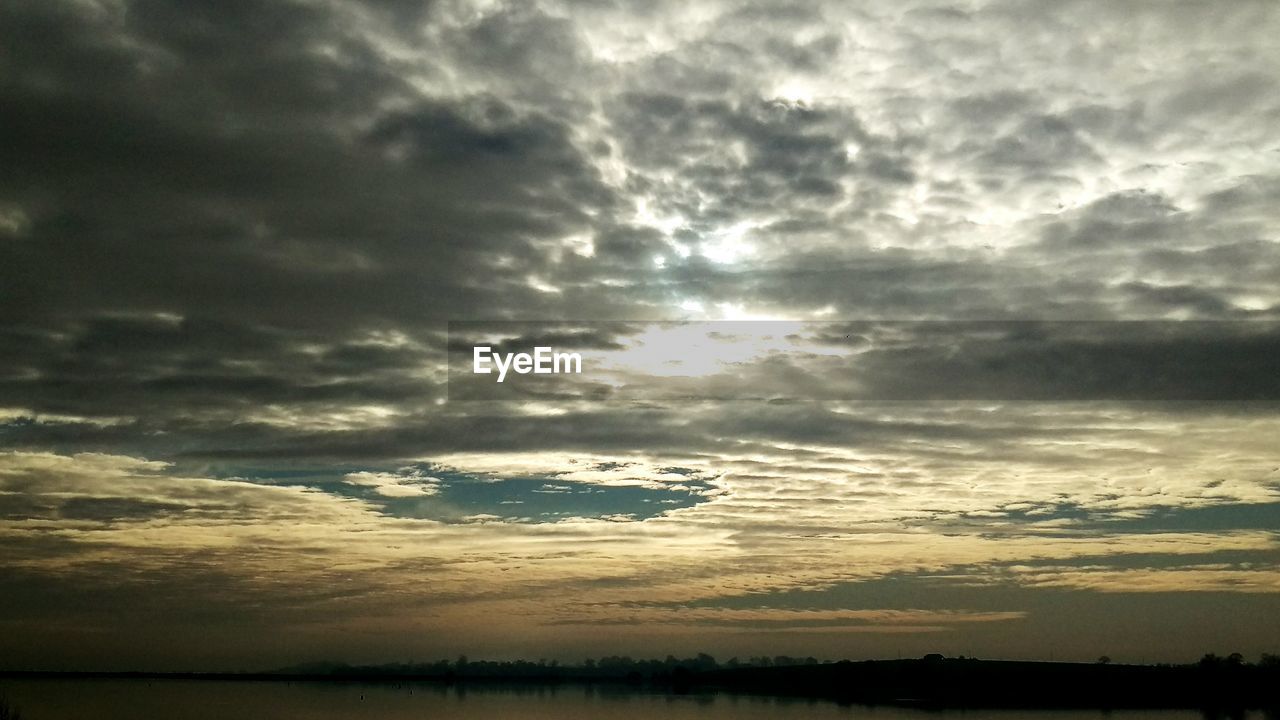 SCENIC VIEW OF SEA AGAINST CLOUDY SKY DURING SUNSET