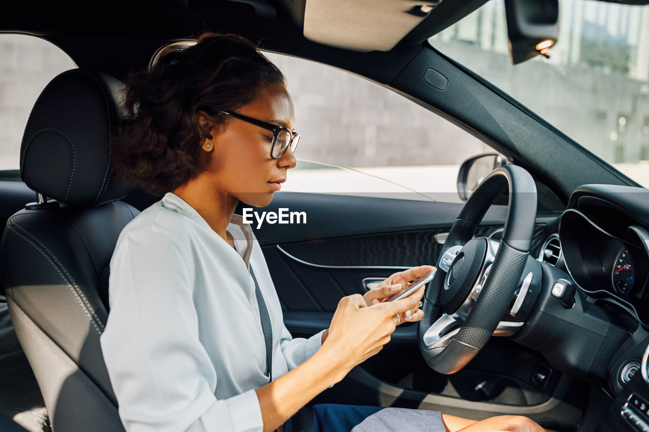 Woman using phone while sitting in car
