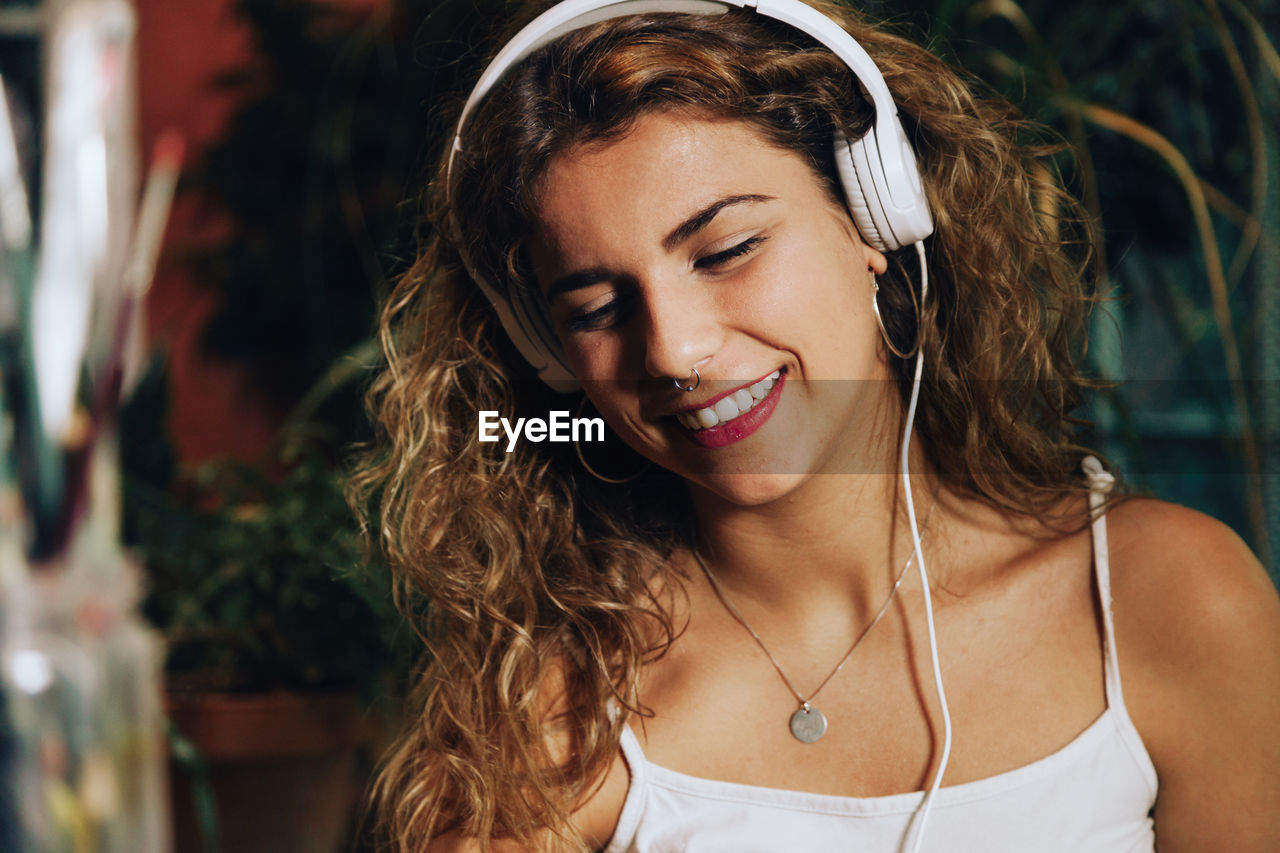 Smiling woman listening music while sitting at home