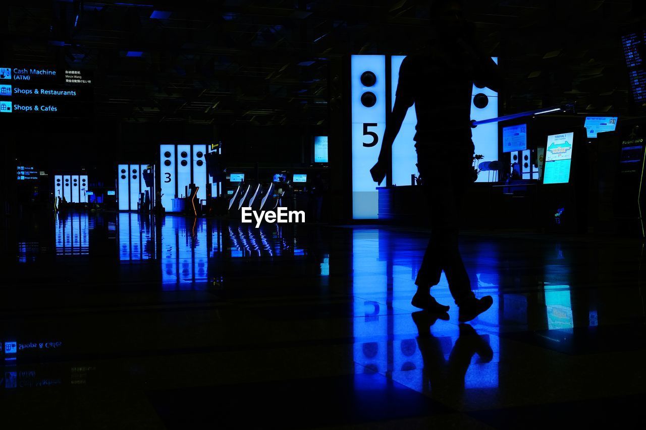 FULL LENGTH OF SILHOUETTE MAN STANDING BY ILLUMINATED STORE