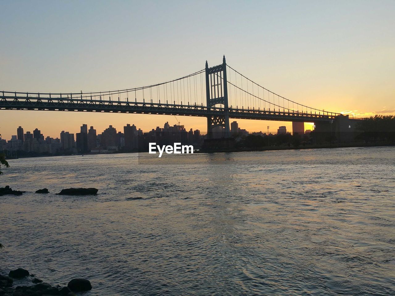 Triborough bridge over river against sky during sunset