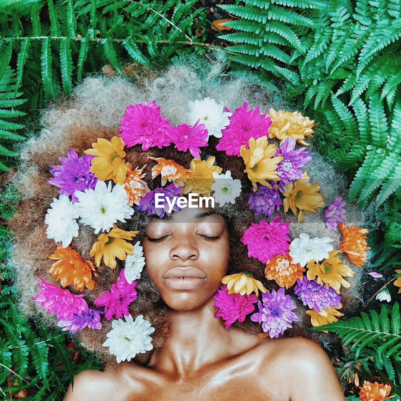 High angle view of woman lying on plants with flowers