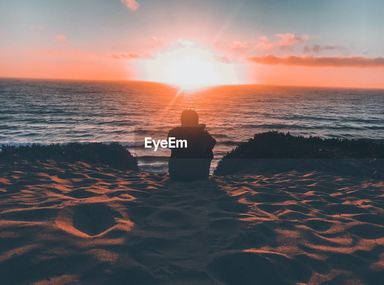 Rear view of man on beach during sunset