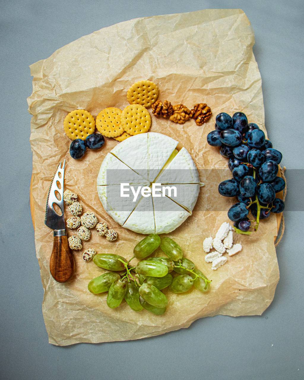 Camembert and brie cheese on a rustic background with grapes, nuts, jam and cracker, italian food