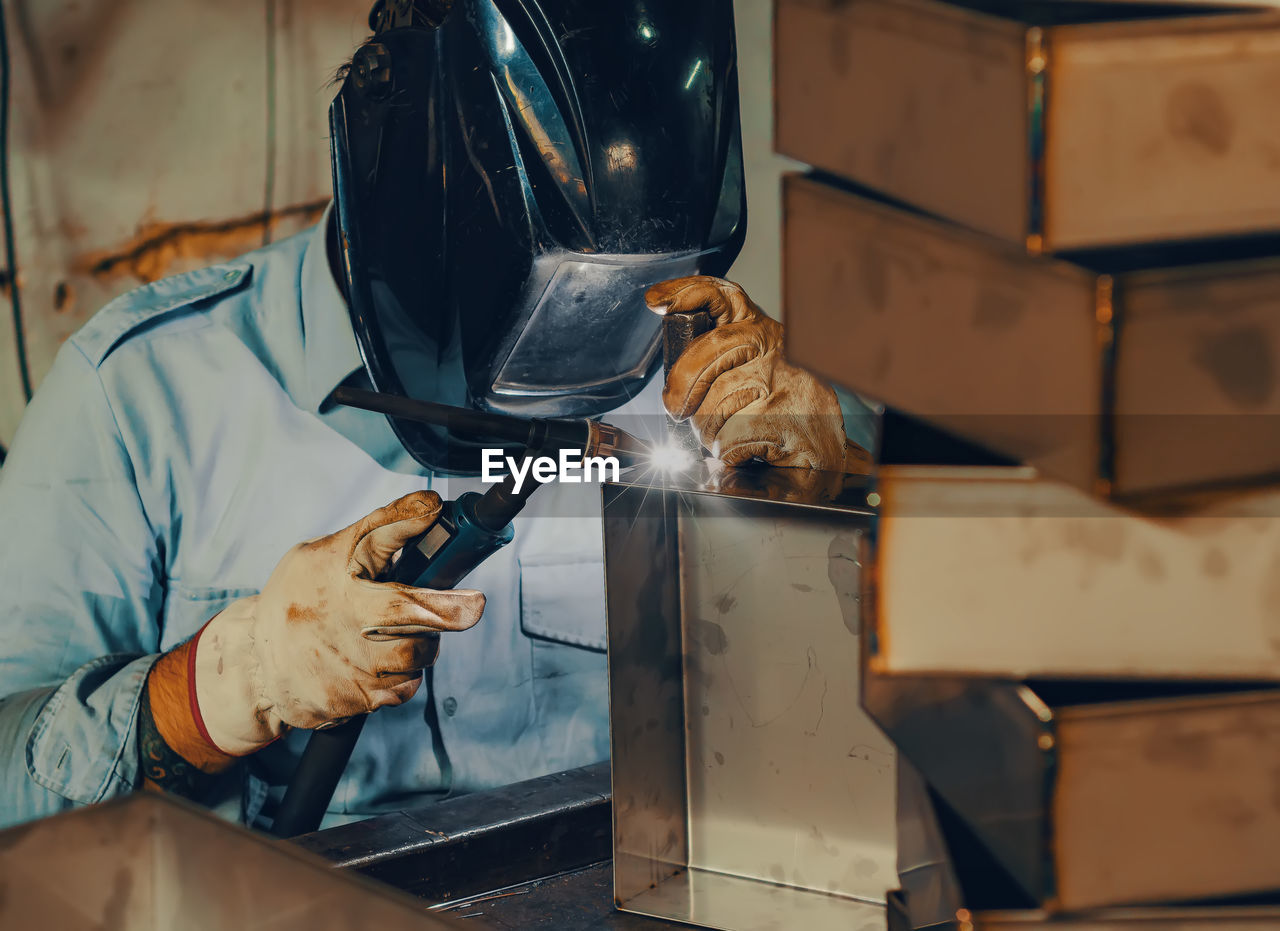 Welder welds a metal box.