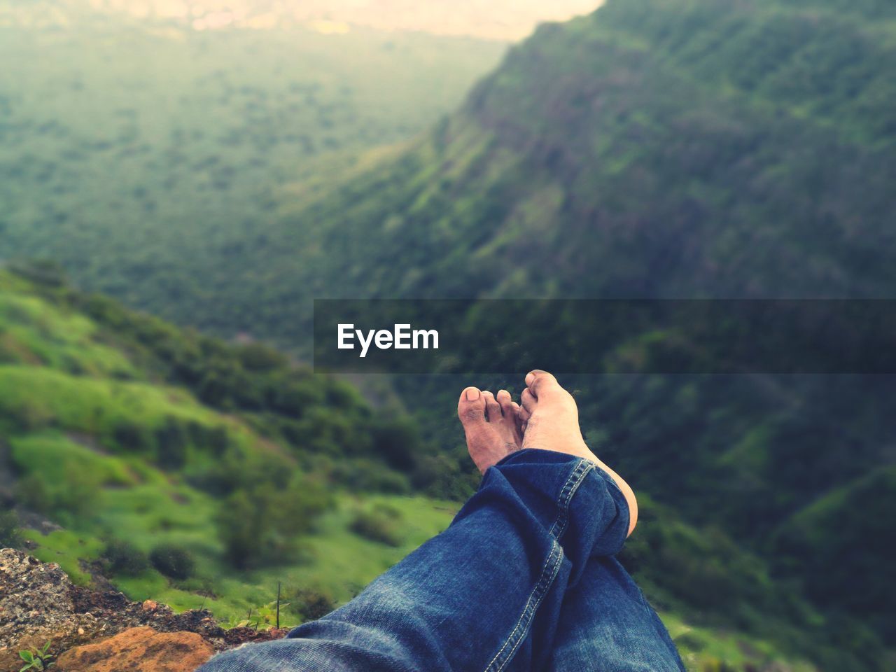 Low section of man relaxing against green mountains