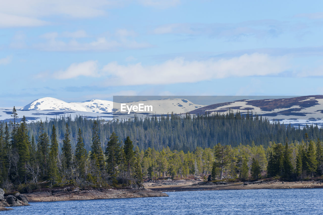 Scenic view of lake by mountains against sky