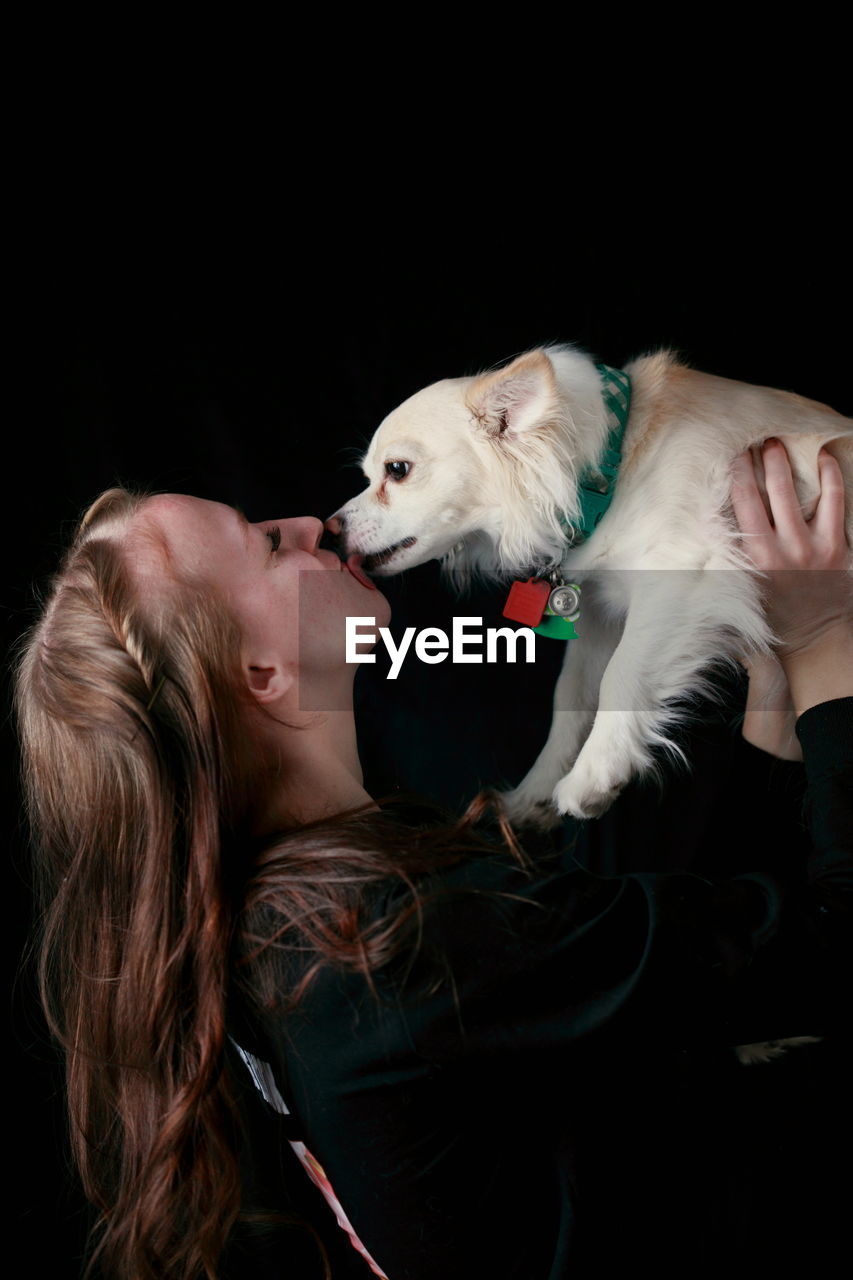 Woman with dog against black background