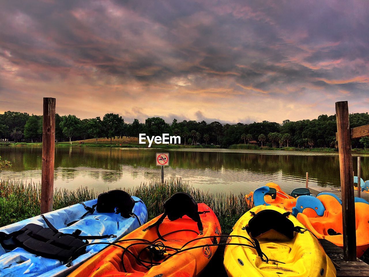 Inflatable rafts on shore at park during sunset against cloudy sky