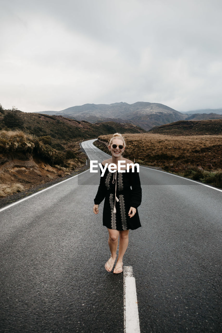 Woman standing on road against sky