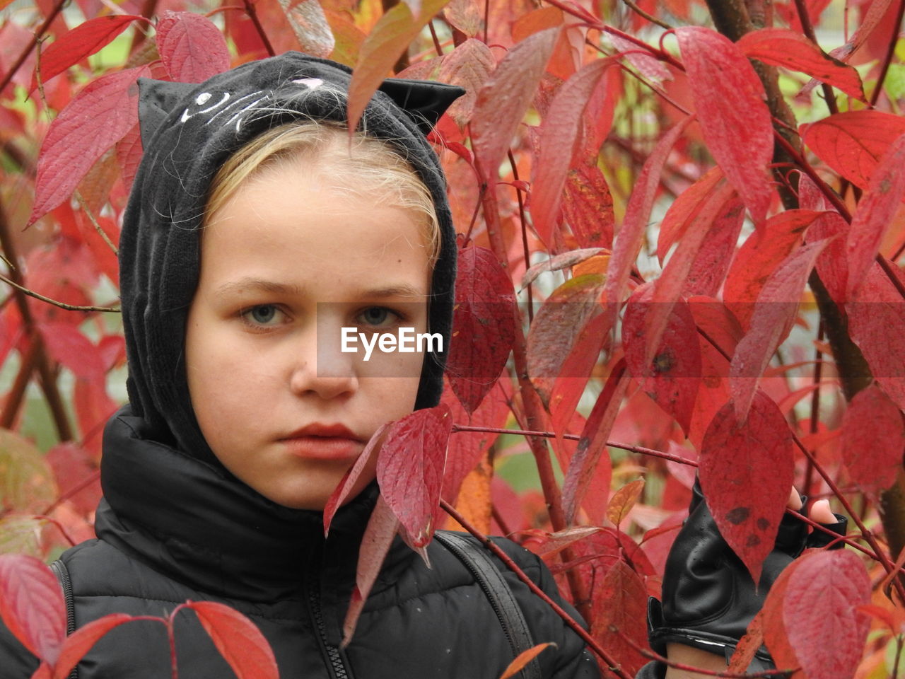 Close-up portrait of girl by autumn leaves