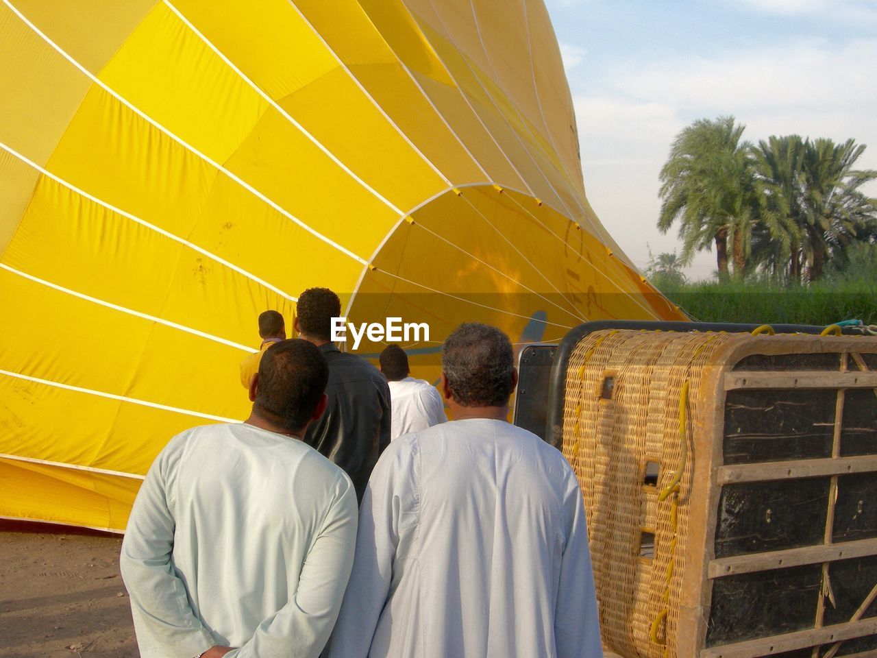 Rear view of people by hot air balloon against sky