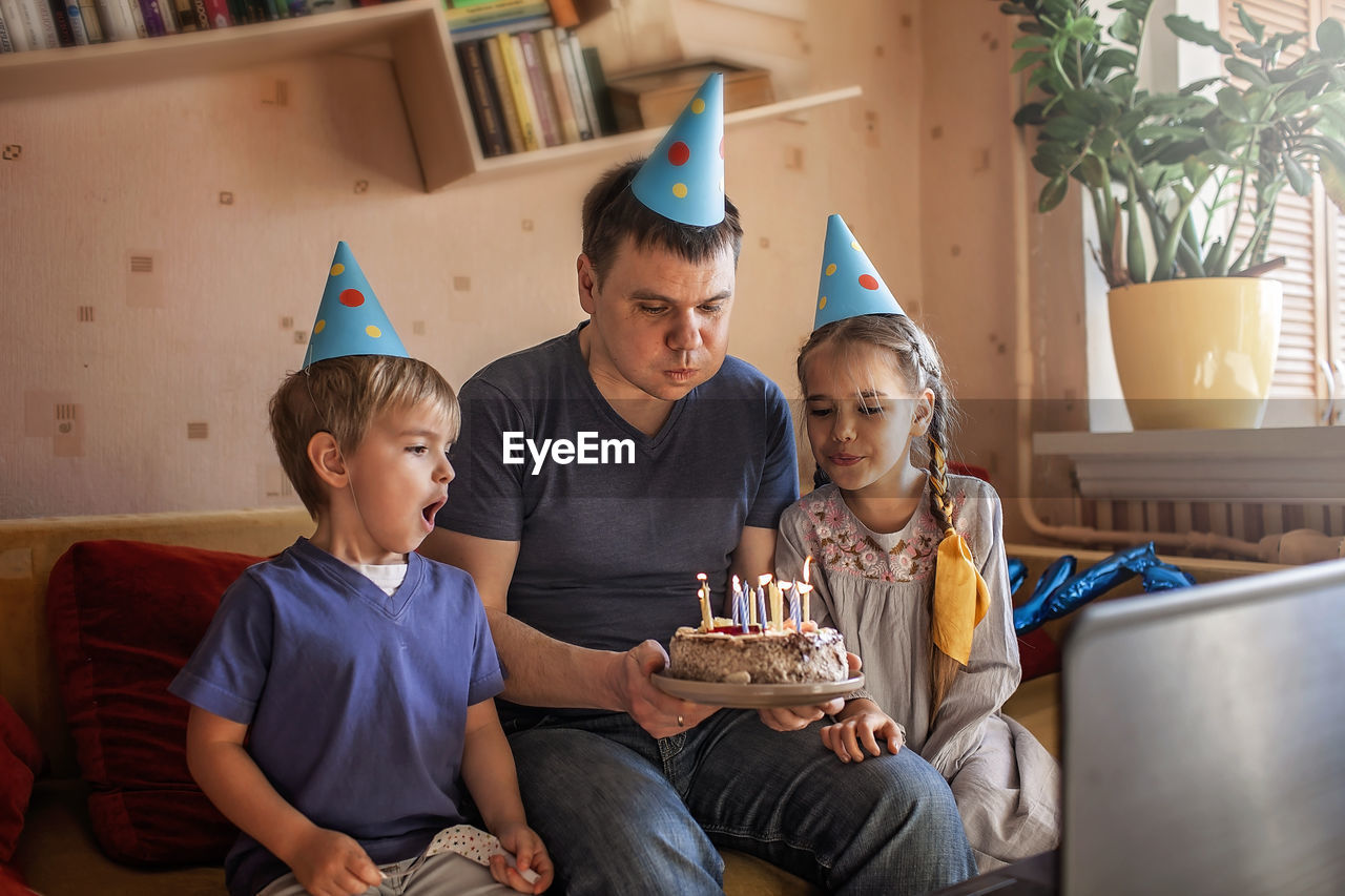 Cheerful father holding cake sitting with kids