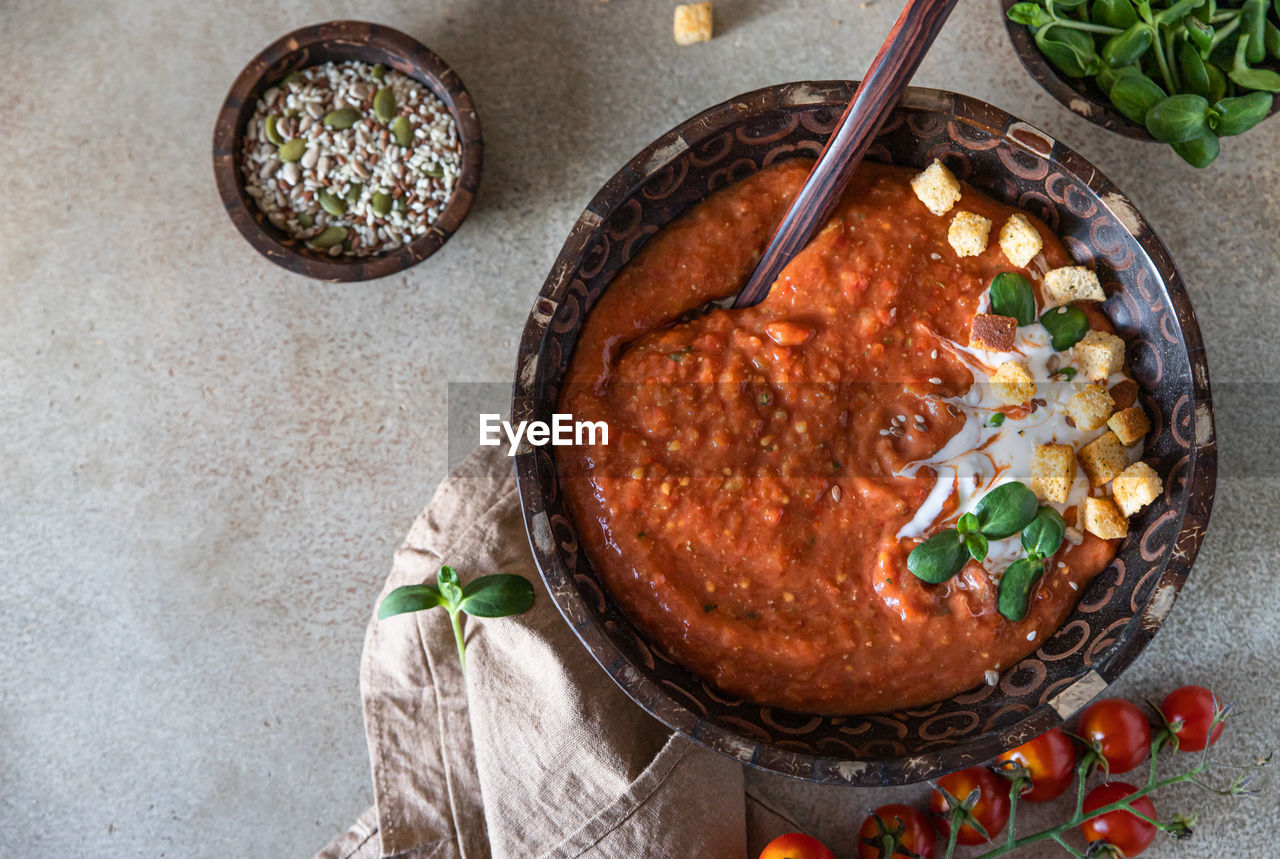 Homemade tomato soup with cream, croutons and microgreen in wooden bowl