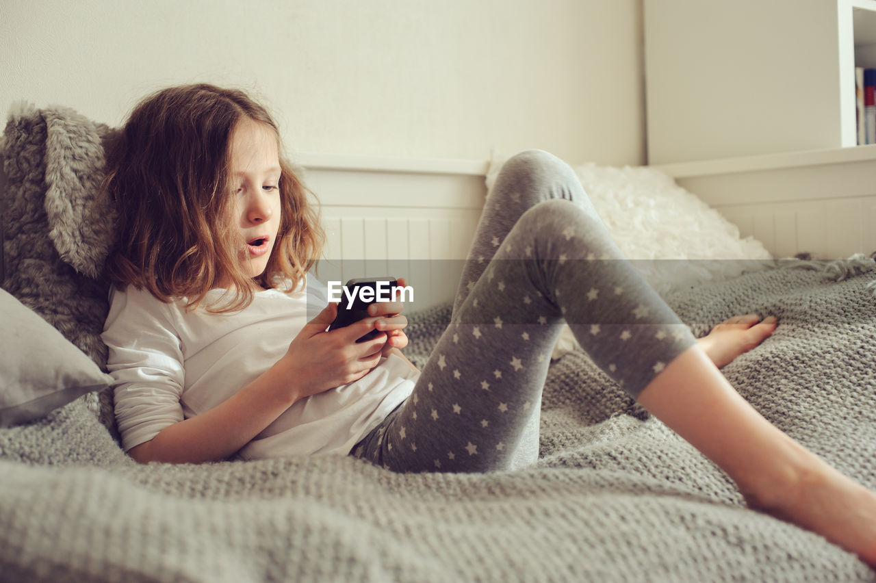 Girl using phone on bed