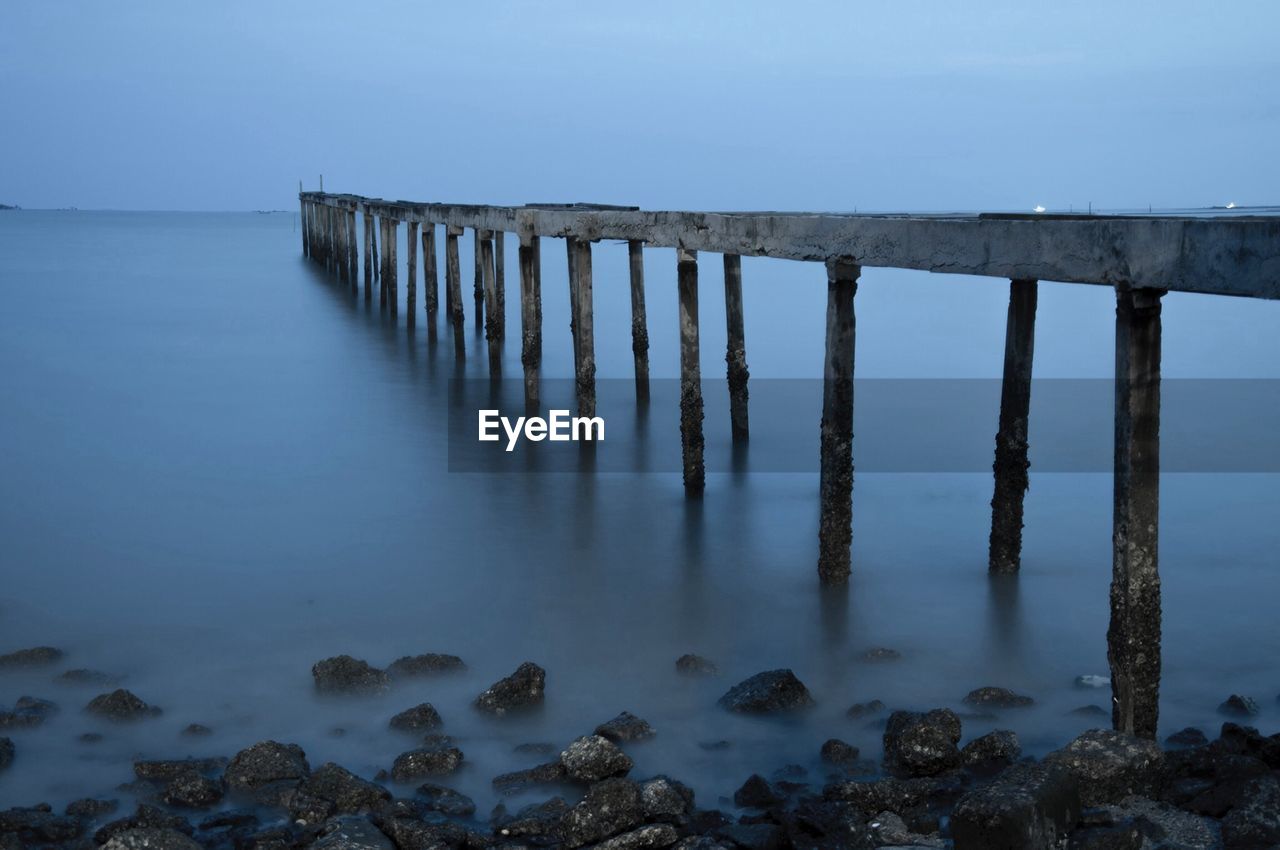 Damaged pier over sea against clear sky