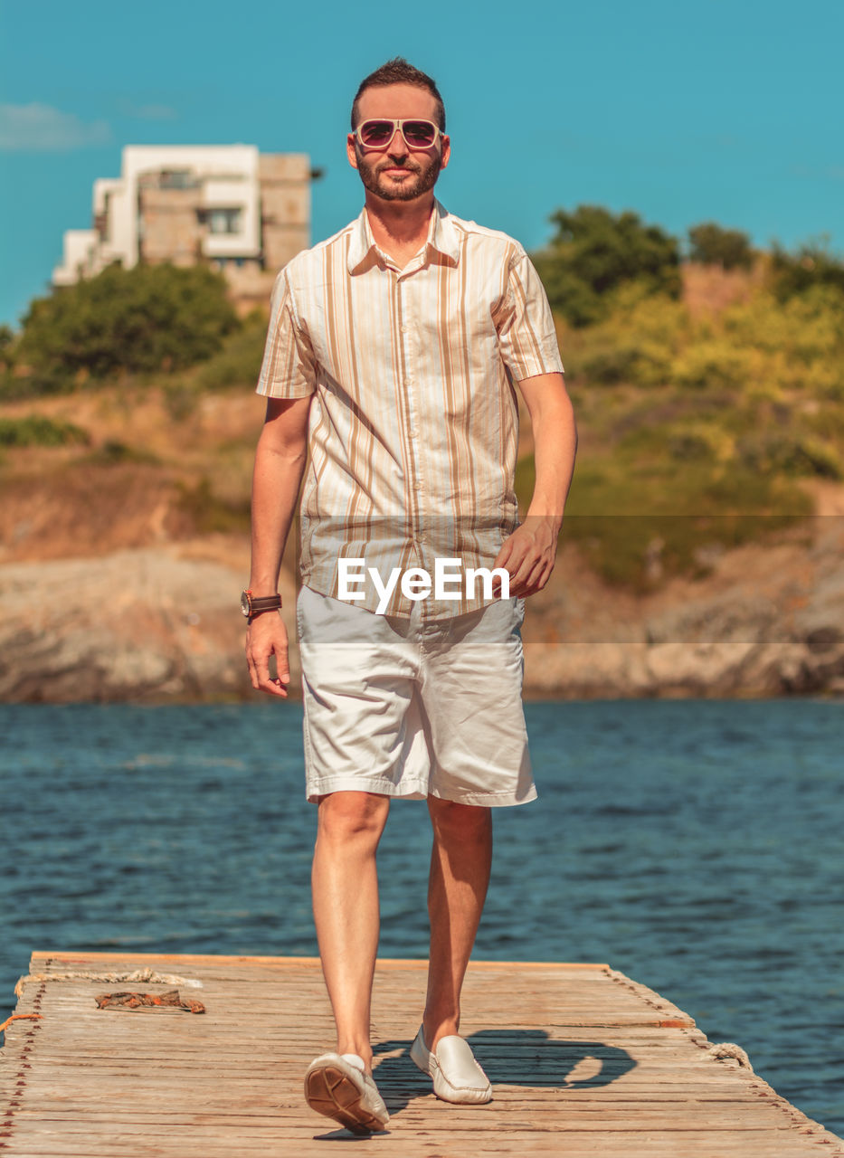 Full length of man wearing sunglasses standing against sea