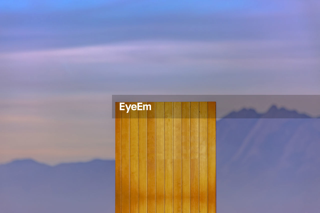 CLOSE-UP OF WOODEN POST AGAINST ORANGE SKY