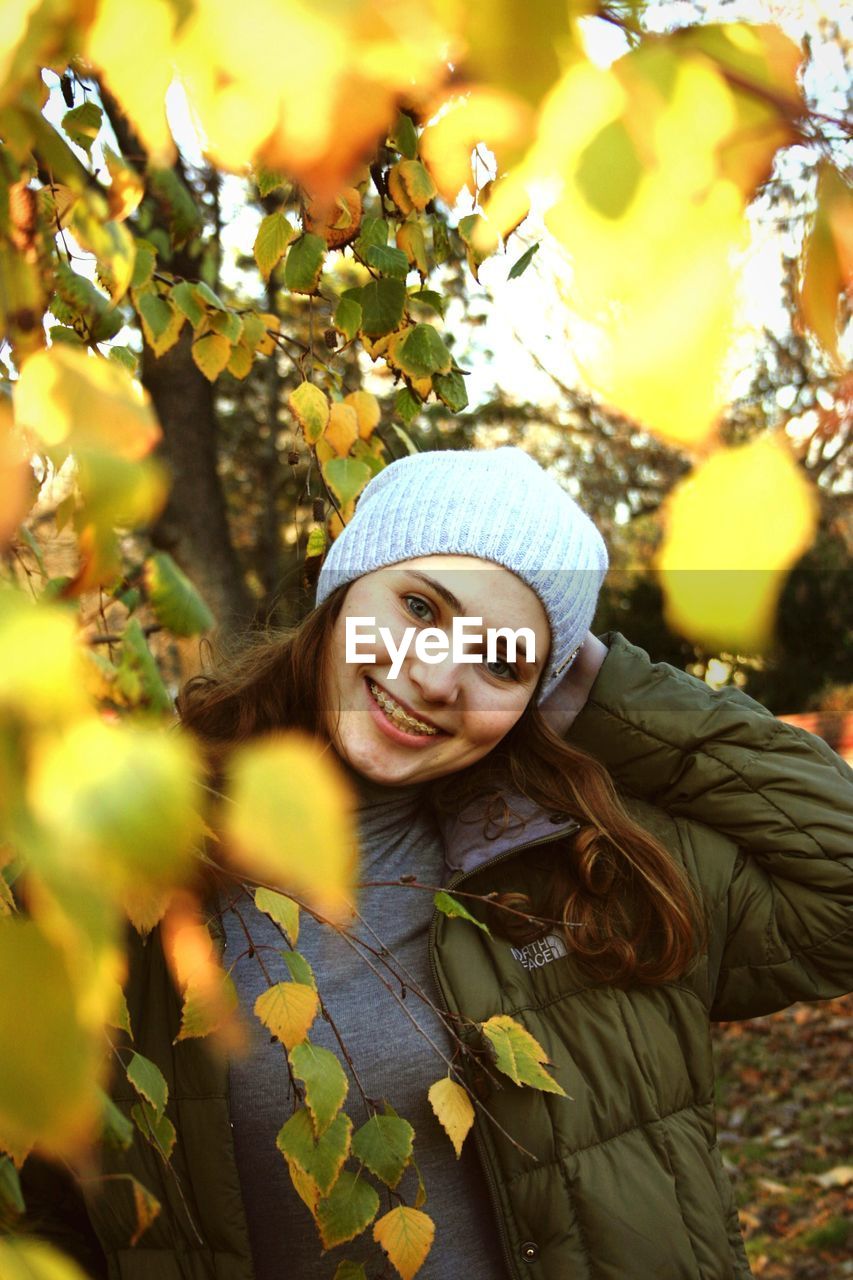 PORTRAIT OF SMILING YOUNG WOMAN IN PARK