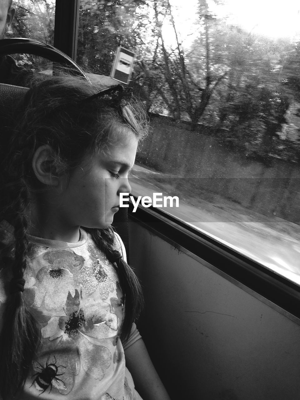 Girl with eyes closed sitting by window in bus