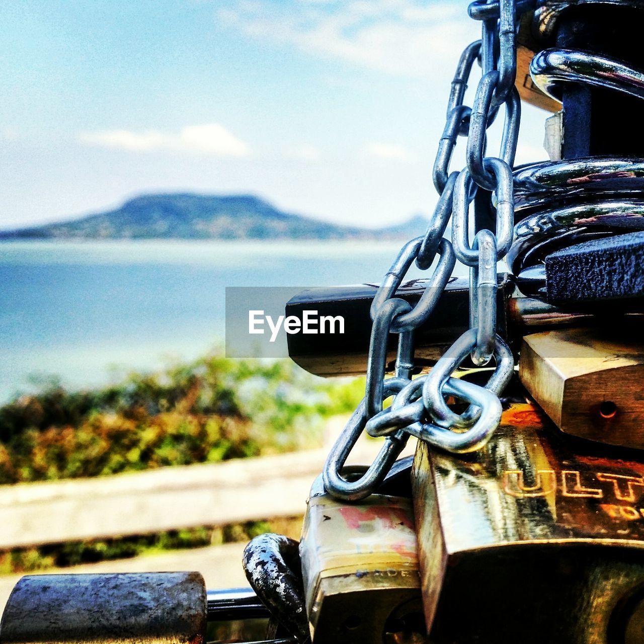 Close-up of metallic chain and locks against sea