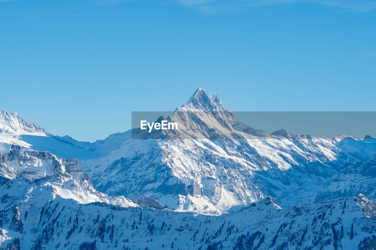 Scenic view of snowcapped mountains against clear blue sky