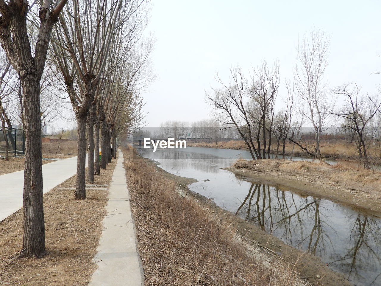 FOOTPATH BY LAKE AGAINST CLEAR SKY DURING WINTER
