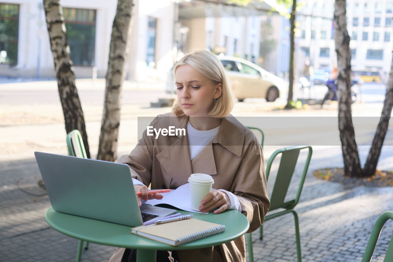 young woman using laptop while sitting on table