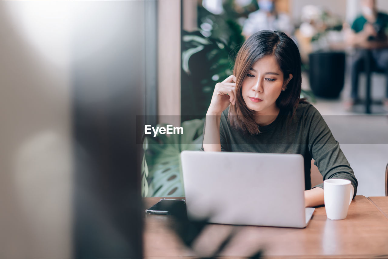 Beautiful woman using laptop while sitting in cafe