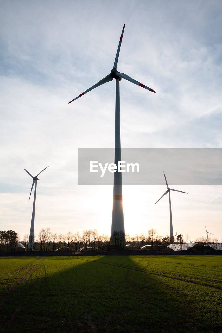 WINDMILL ON FIELD BY WINDMILLS AGAINST SKY