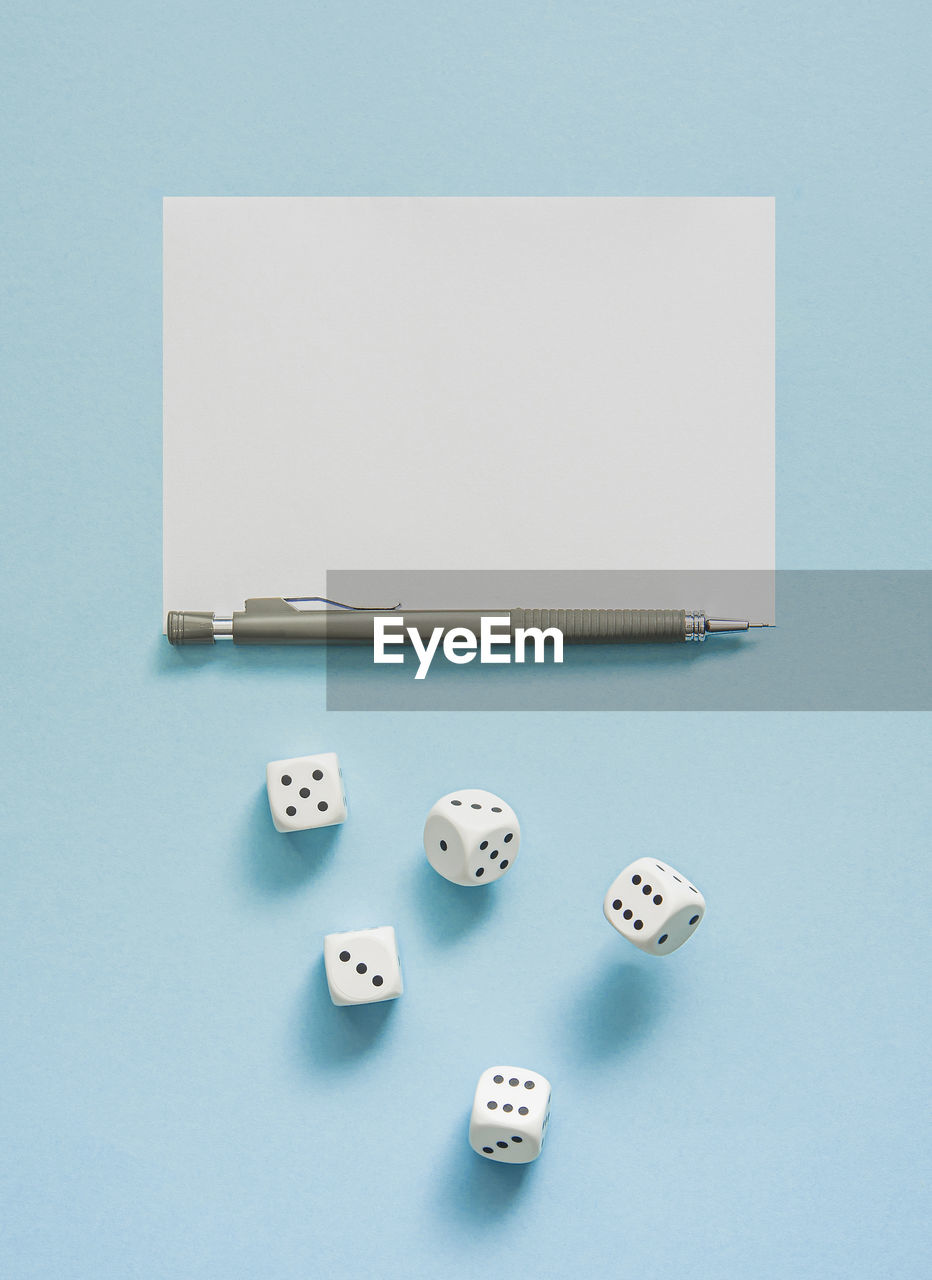 Yahtzee game in progress. rolling dice, pencil and score sheet on a blue background.