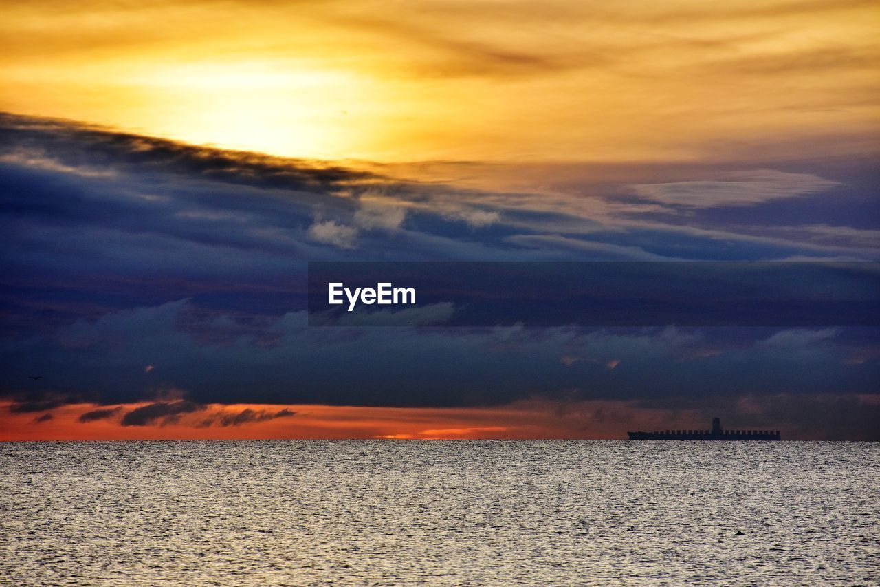 Scenic view of sea against dramatic sky during sunset