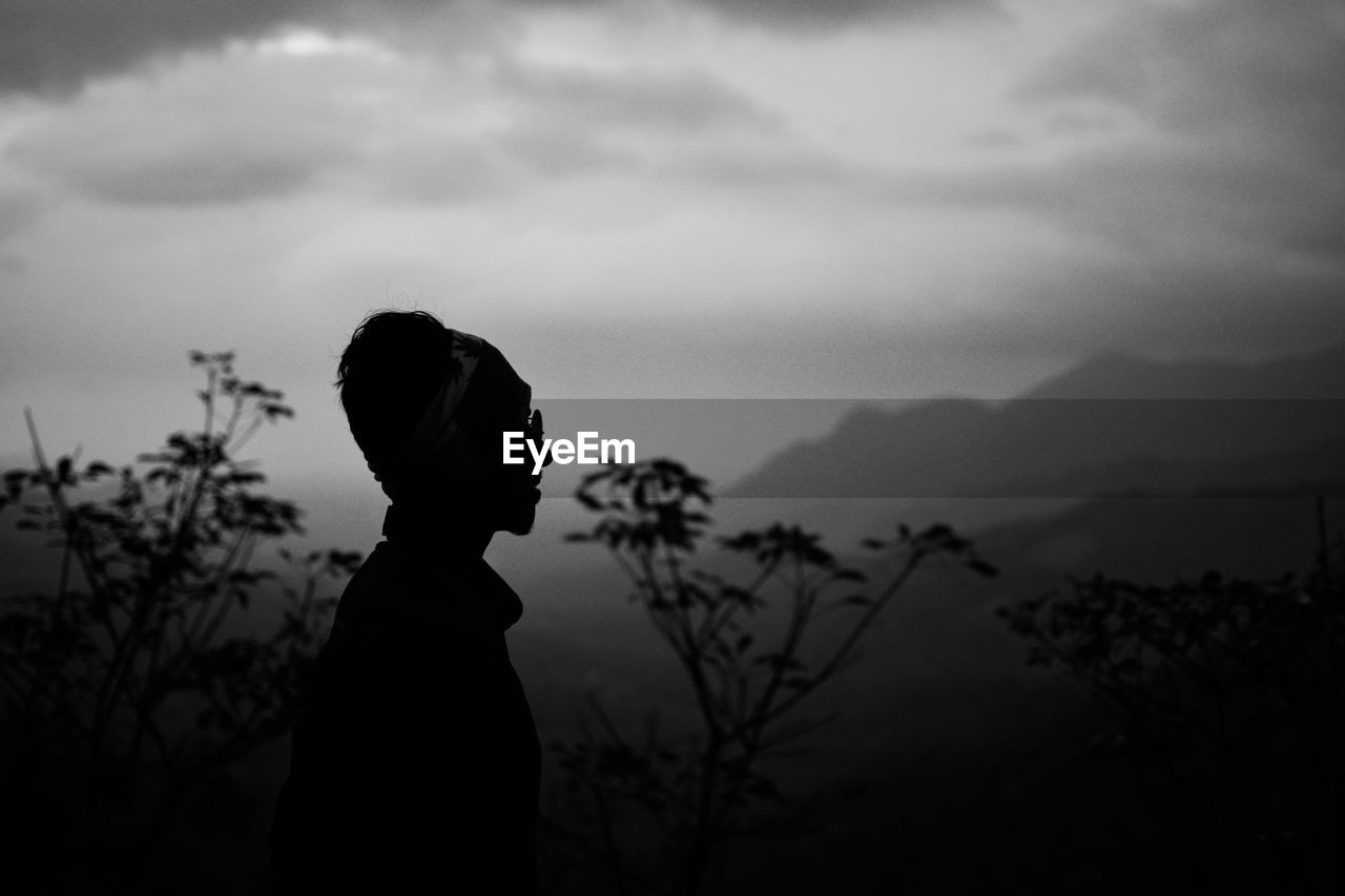 Side view of silhouette man standing against sky
