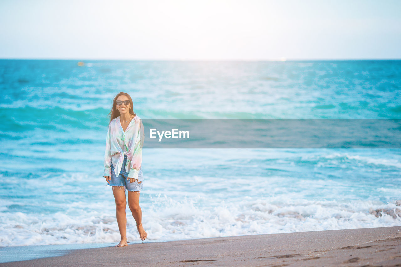 full length of young woman standing at beach