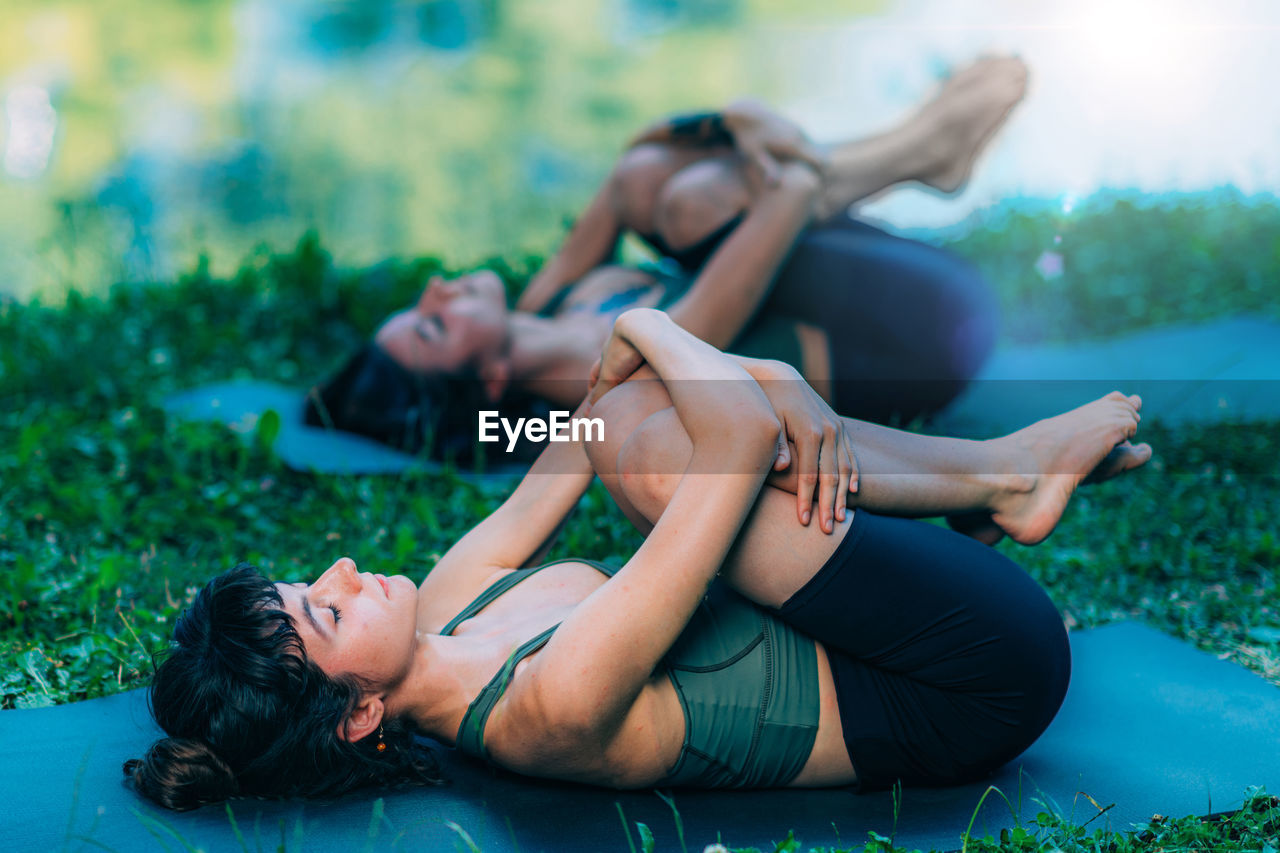 Yoga women by the water. wind relieving pose.