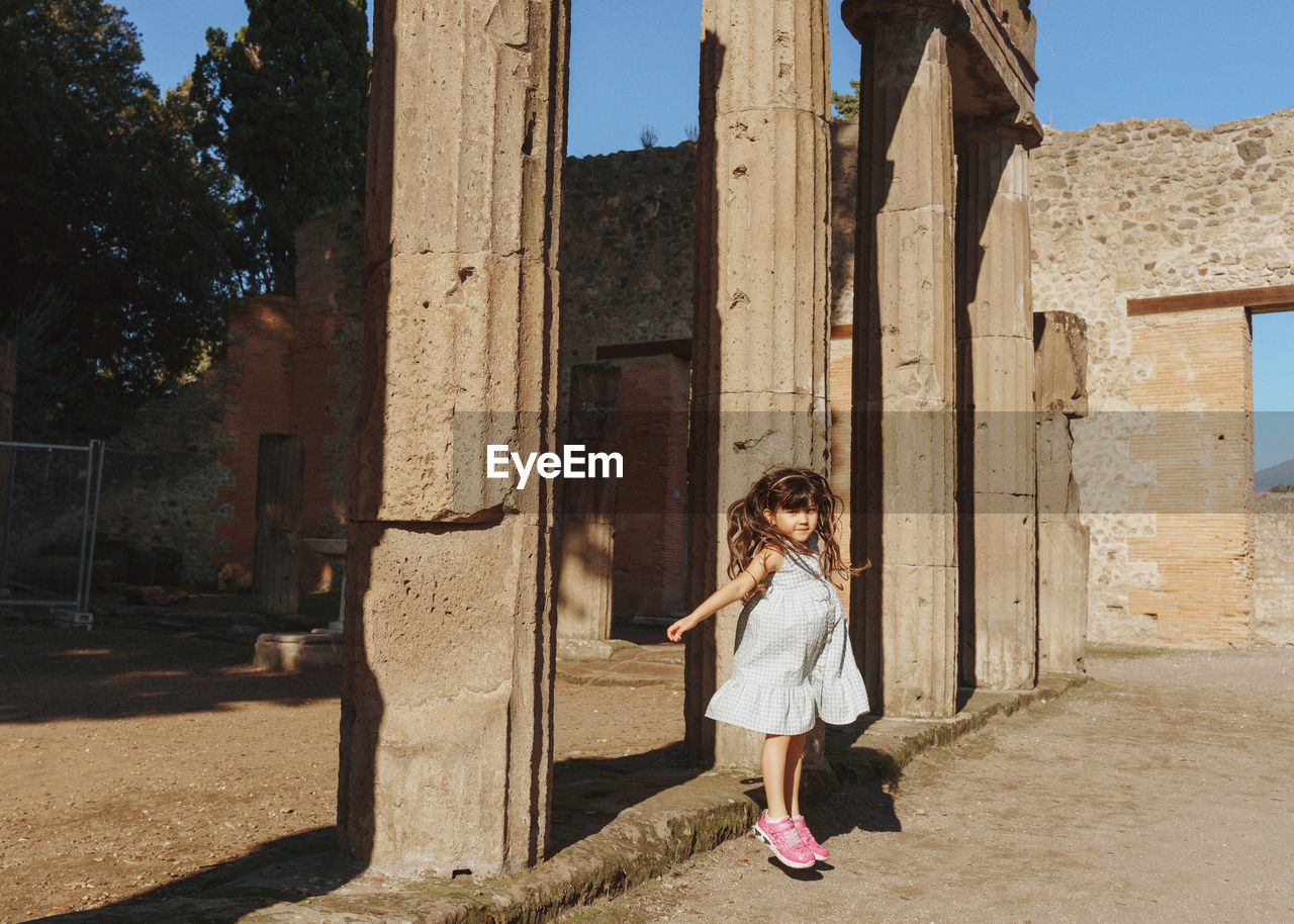 Rear view of girl  standing between ruins in pompei