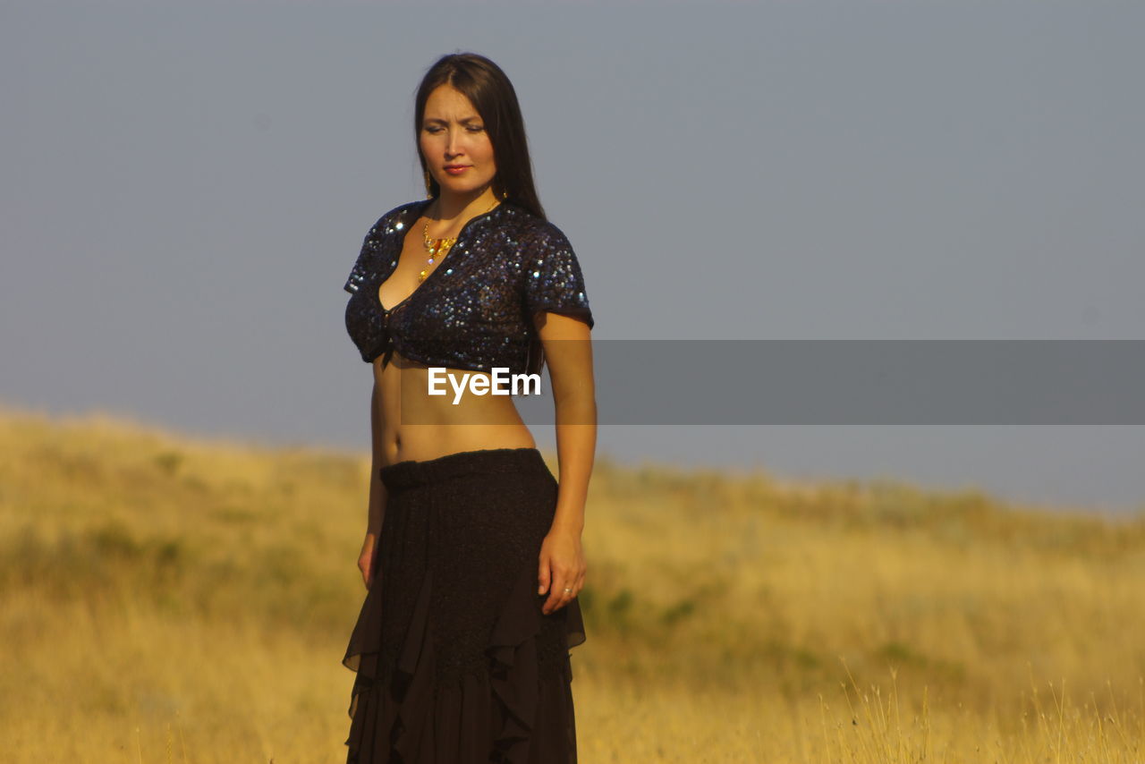 Woman standing on field against clear sky