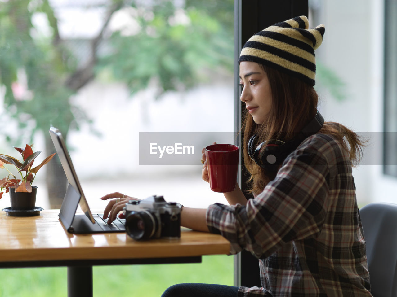 Young woman using digital tablet while sitting on table