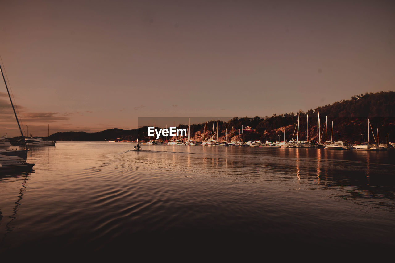 Sailboats in sea at sunset