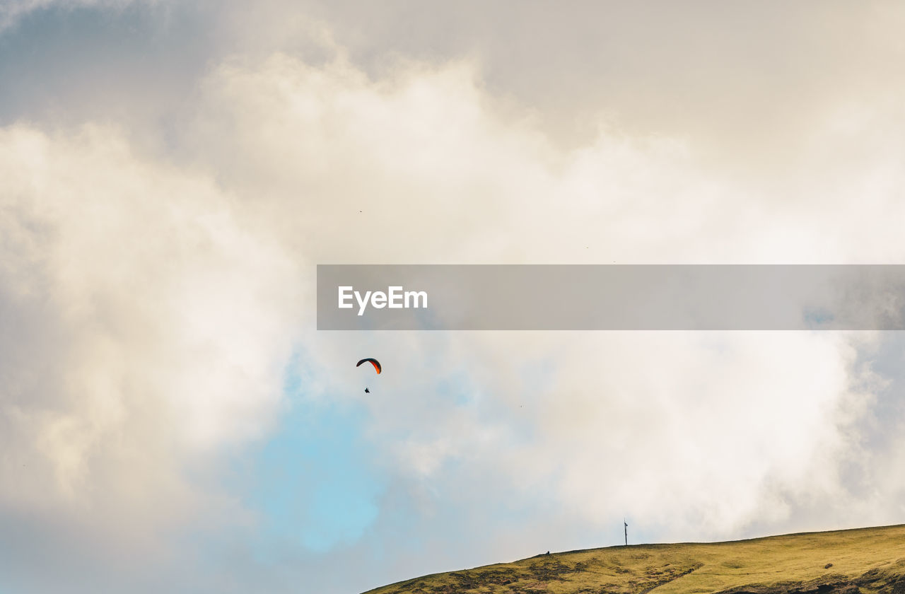 Low angle view of person paragliding against sky