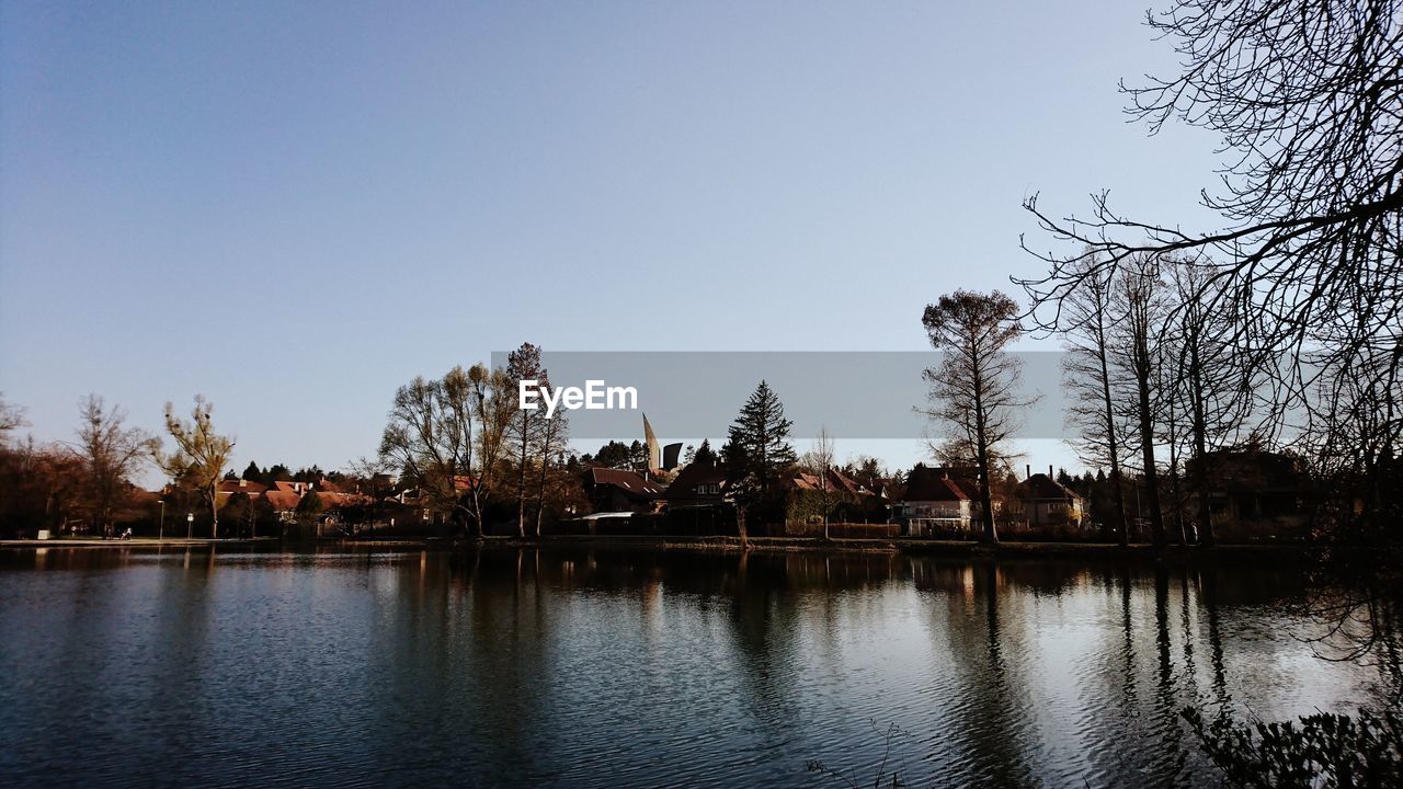 Scenic view of lake by buildings against clear sky