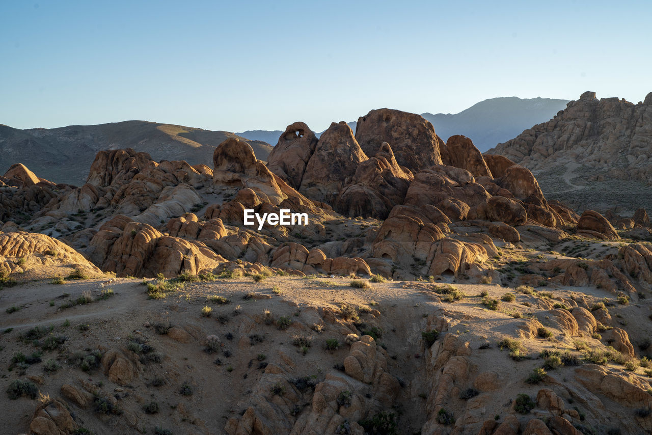 Scenic view of arid landscape against clear sky with distant mountains