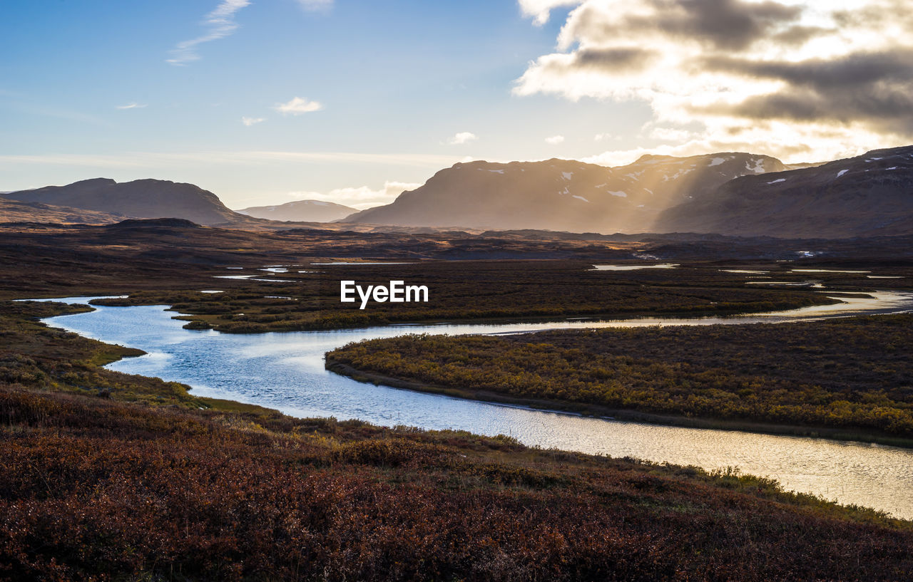 Scenic view of river and mountains against sky