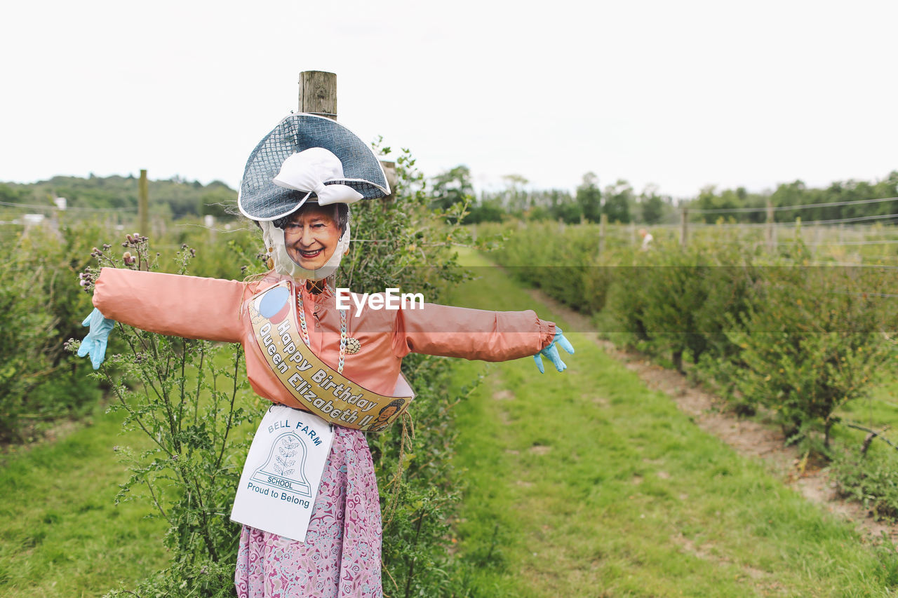 WOMAN STANDING ON GRASSY FIELD