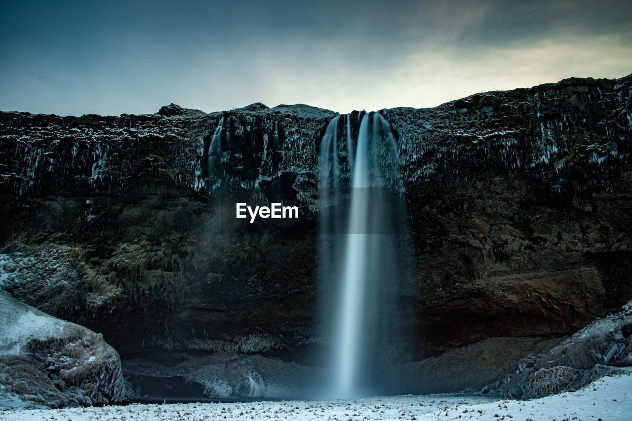 SCENIC VIEW OF WATERFALL AGAINST SKY DURING SUNRISE