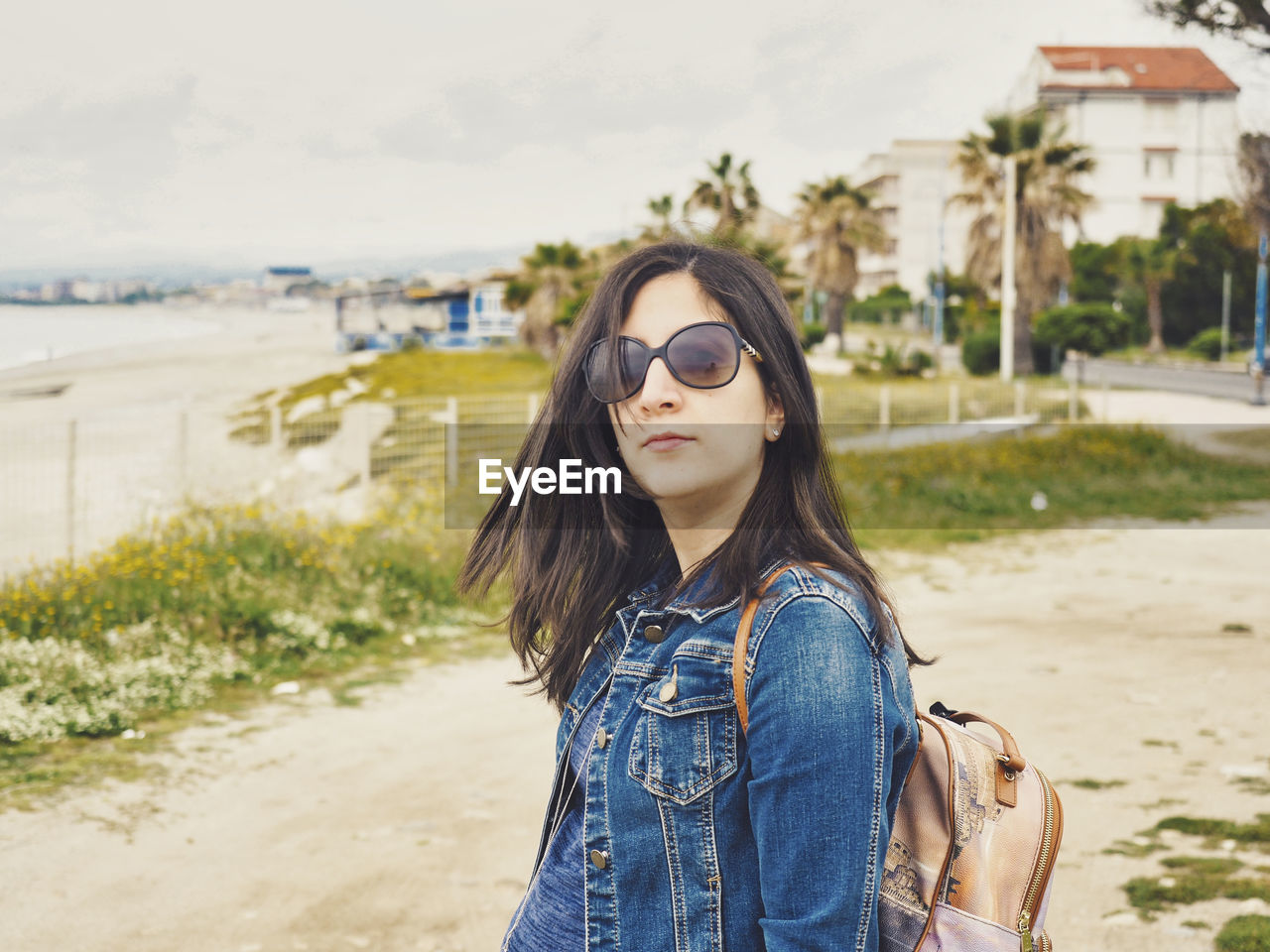 Portrait of young woman wearing sunglasses while standing at beach