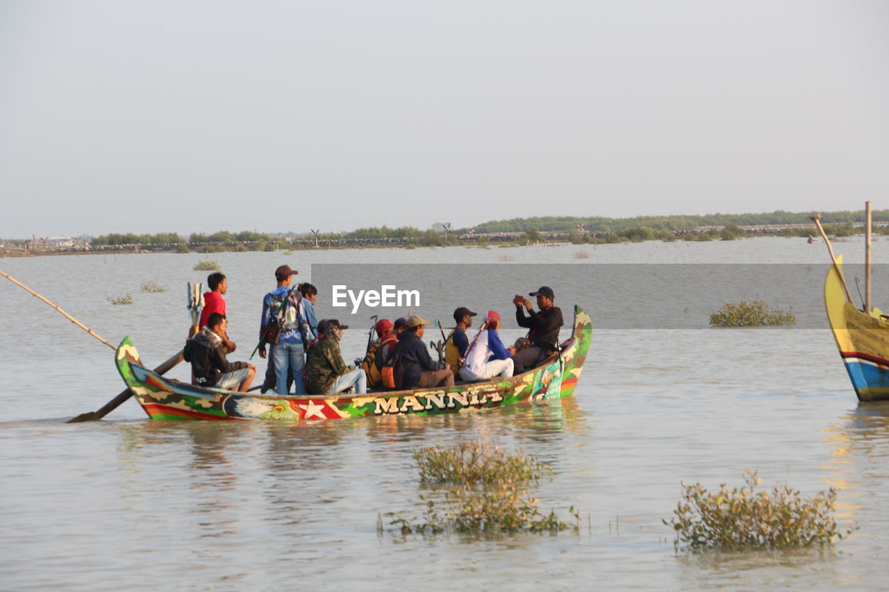 PEOPLE IN BOAT ON SEA AGAINST SKY