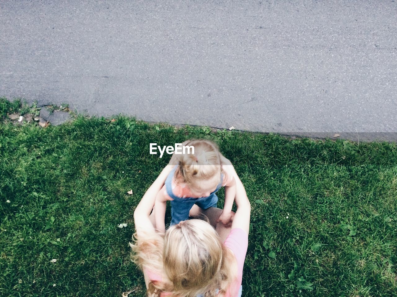 High angle view of mother and daughter embracing on grass